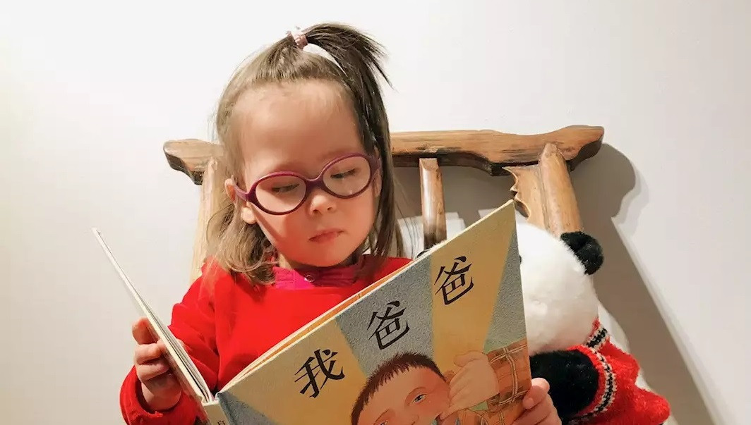 En flicka läser en bilderbok.