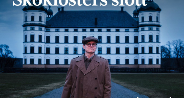 En man håller i en lykta med ett slott i bakgrunden.