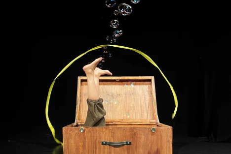 två ben och såpbubblor kommer upp ur trälåda och gult band i cirkel bakom