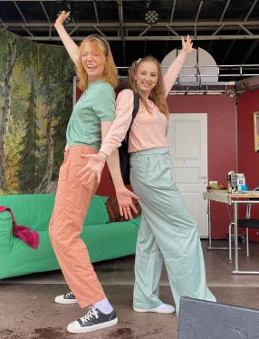 Två artister på en scen med soffa och kulisser