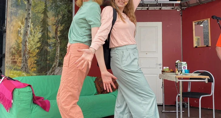 Två artister på en scen med soffa och kulisser