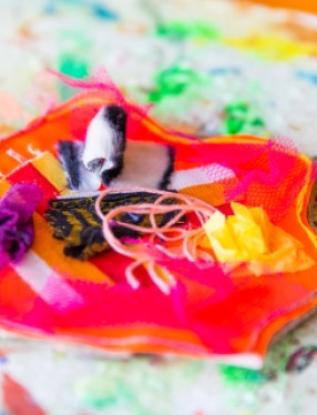 Handarbete av tygbitar, trådar och annat material i olika färger.