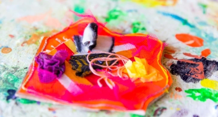 Handarbete av tygbitar, trådar och annat material i olika färger.