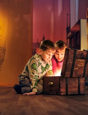 Två barn tittar ner i en skattkista som lyser