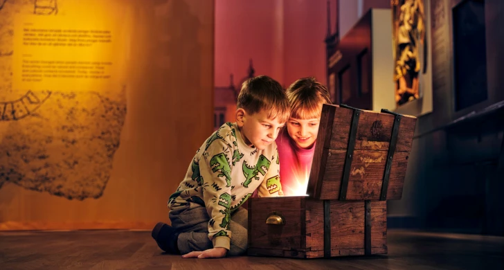 Två barn tittar ner i en skattkista som lyser