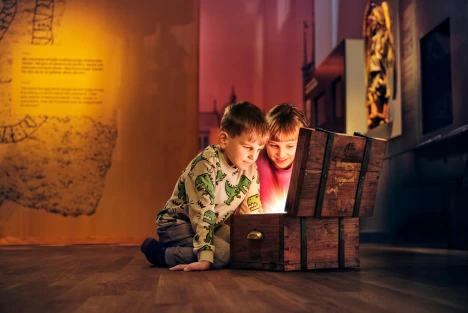 Två barn tittar ner i en skattkista som lyser