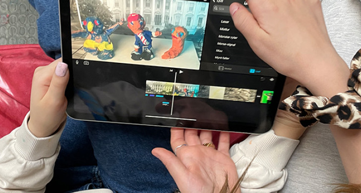 Händer håller i surfplatta med animerad film