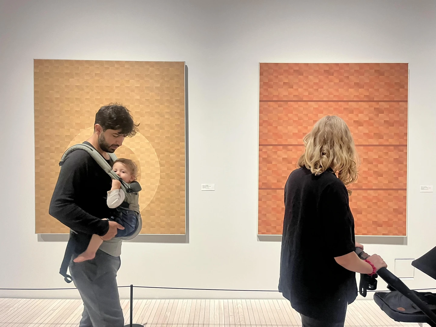 Föräldrar med barn i bärsele som tittar på konst.