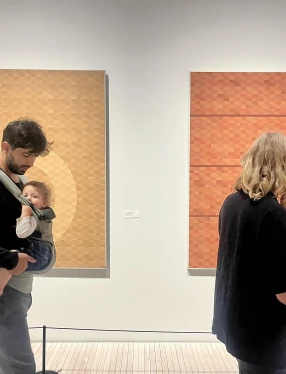 Föräldrar med barn i bärsele som tittar på konst.