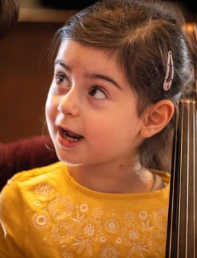 Liten tjej som spelar cello. Fotografi.