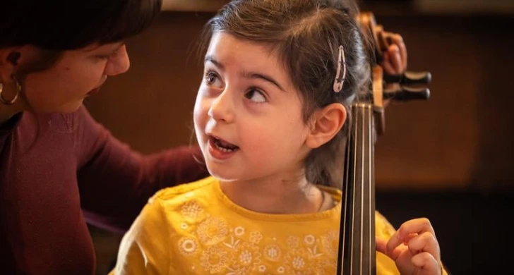 Liten tjej som spelar cello. Fotografi.