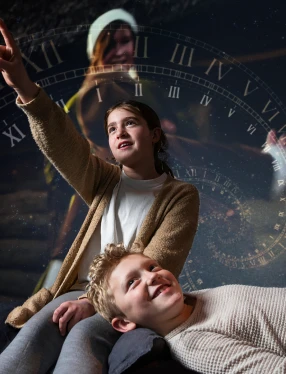 Två barn framför historisk bild. Ett barn pekar.