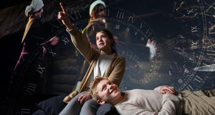 Två barn framför historisk bild. Ett barn pekar.